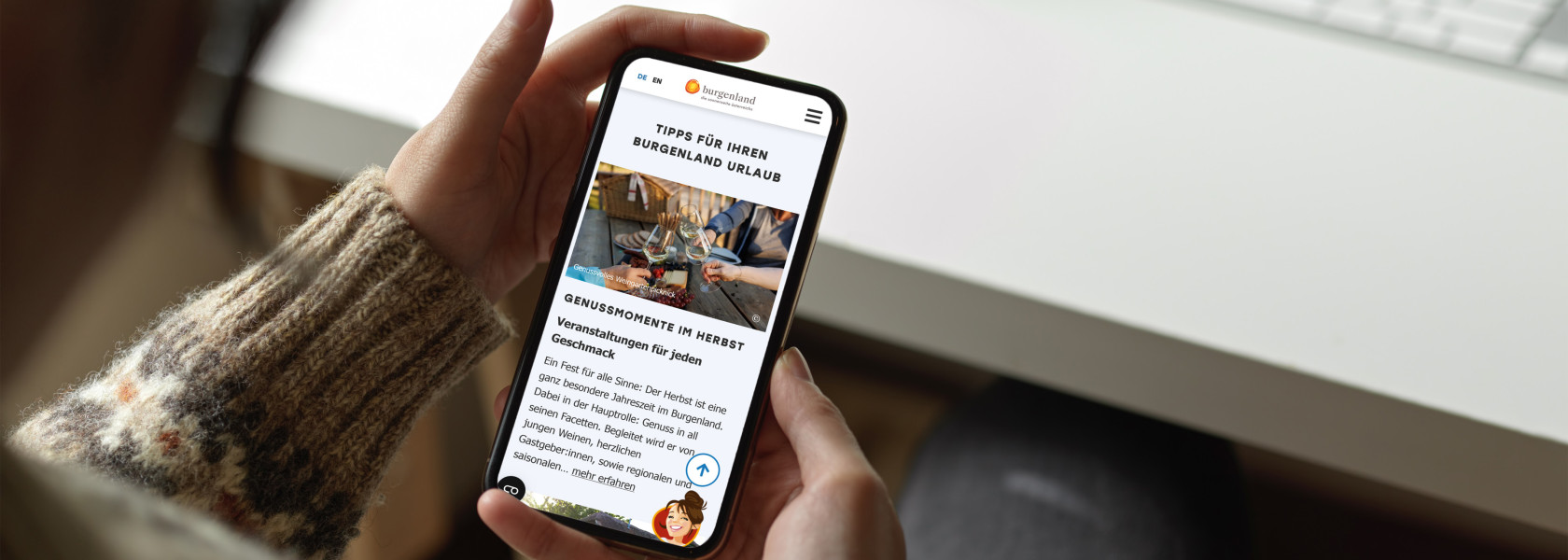 Person die ein Smartphone mit geöffneter Website von Burgenland Tourismus in beiden Händen hält