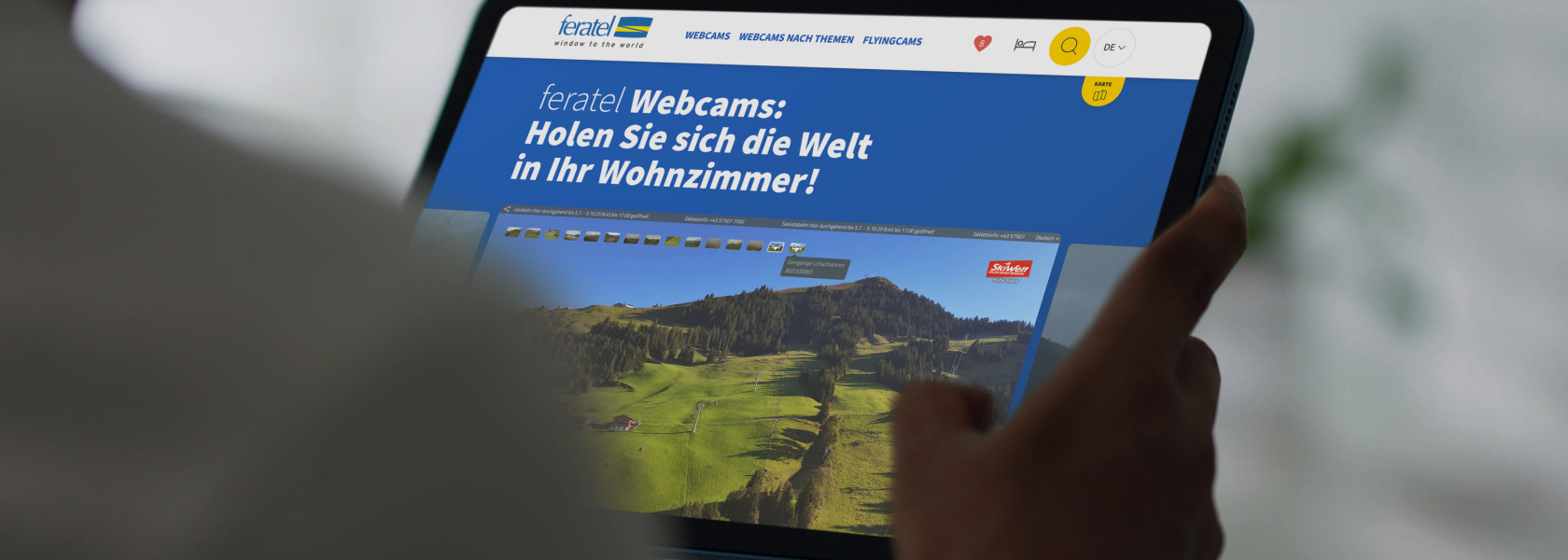 Ein Tablet das in der Hand gehalten wird, welches einen Ausschnitt der Feratel Website zeigt