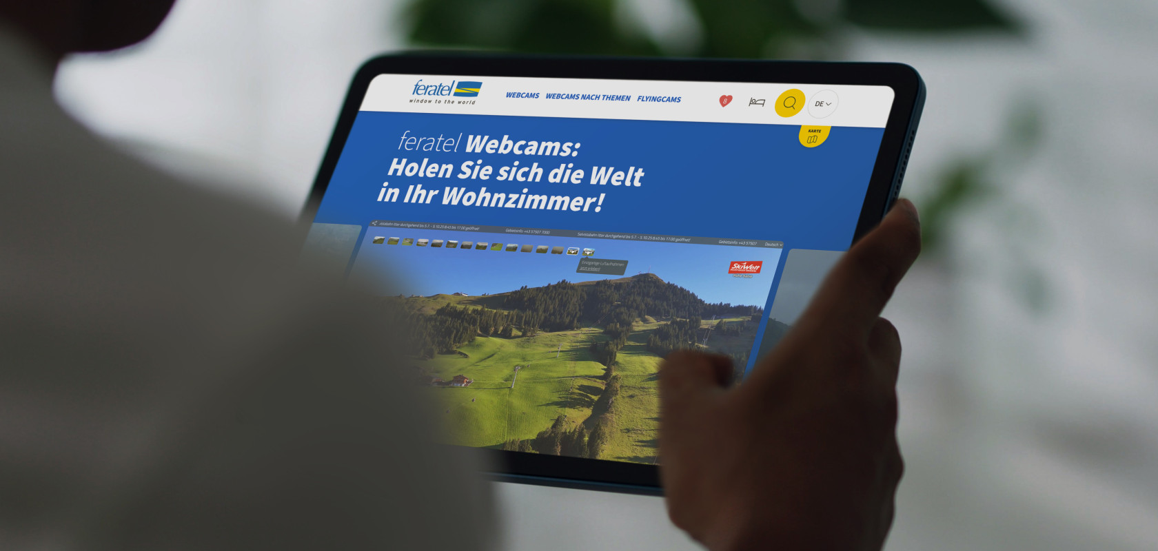 Ein Tablet das in der Hand gehalten wird, welches einen Ausschnitt der Feratel Website zeigt